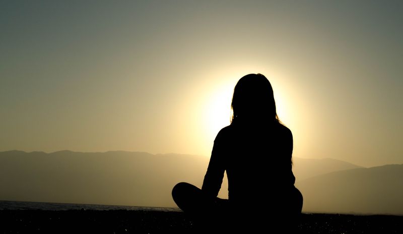 Silhouette of a woman watching a sunset.