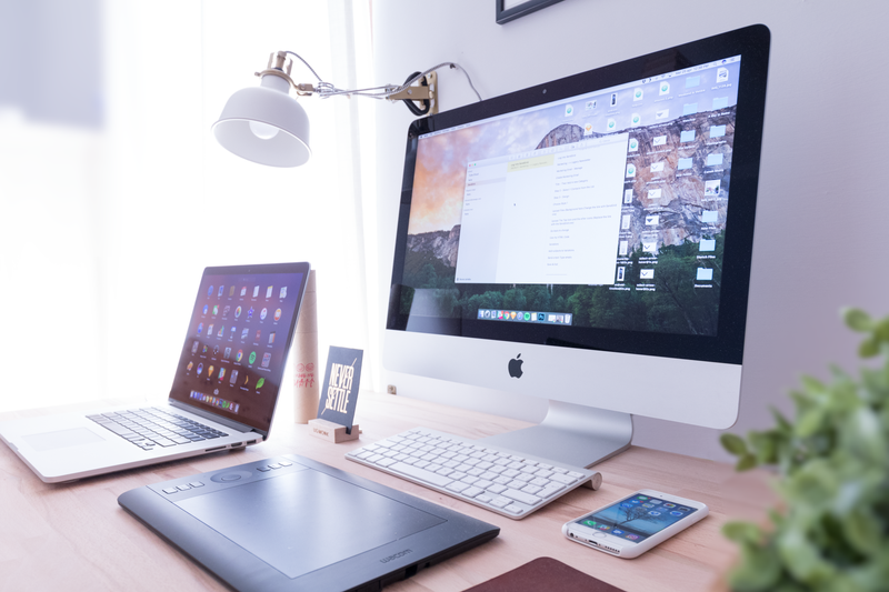 A desktop, laptop, and phone on a desk.