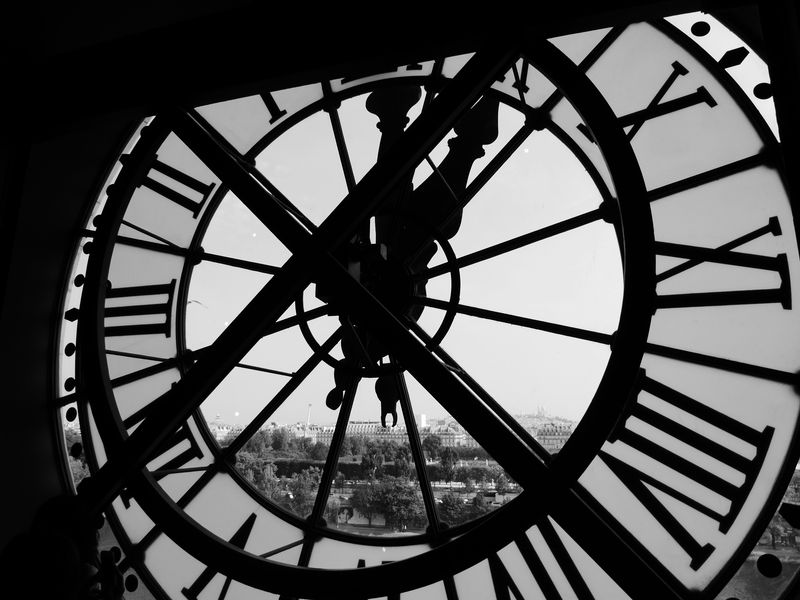 A view from inside a large building-side clock looking out at a city.