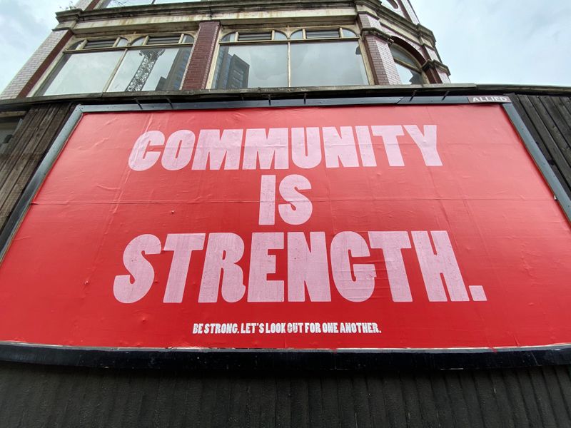 Red sign says, 'Community is strength. Be strong. Let's look out for one another.'