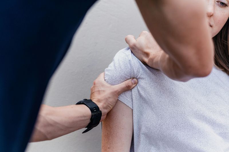 A physiotherapist applying pressure to patient's shoulder to aid in injury recovery.