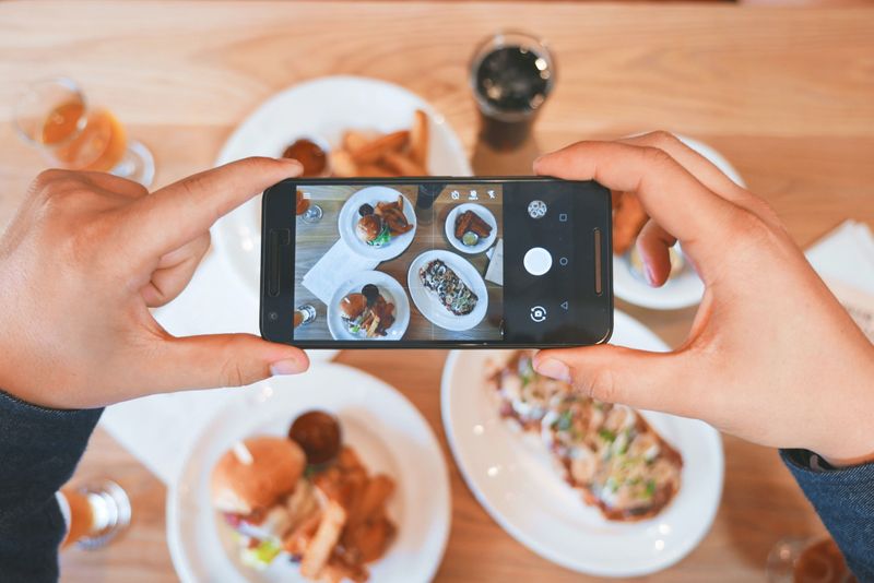 A food photographer using a phone to photograph a dinner.