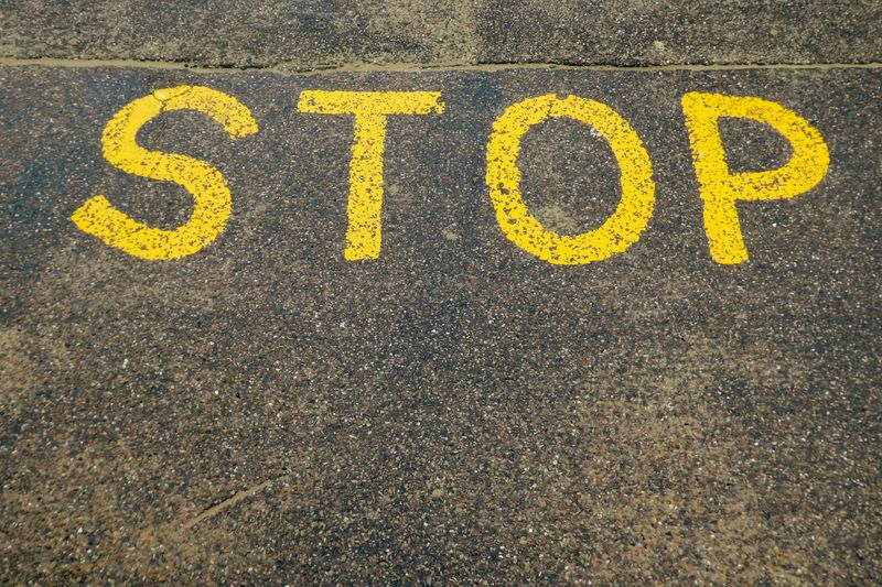 The letters 'STOP' spray-painted on a tar road.