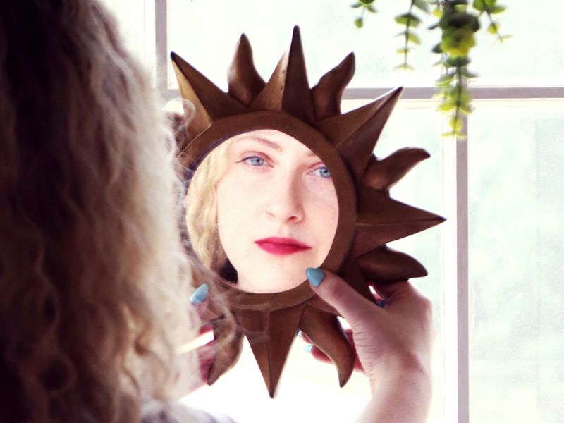 A woman looking at her own reflection in a mirror.