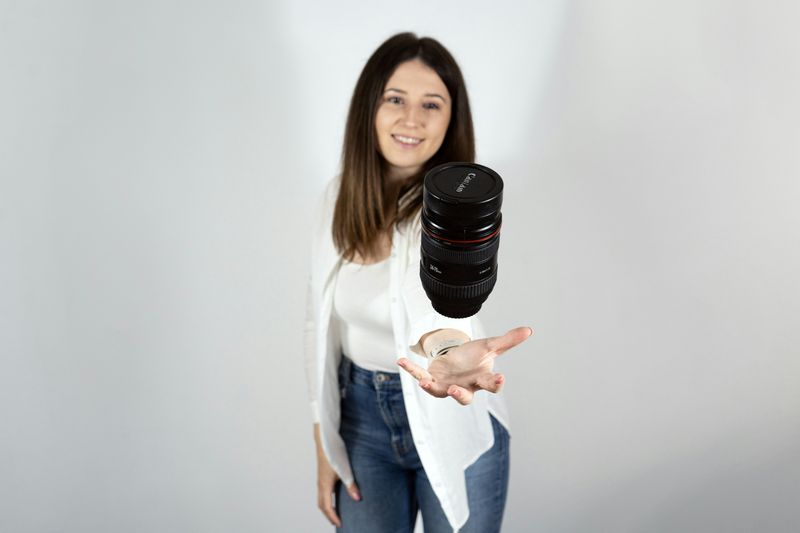 A fashion photographer tossing and catching a lens in mid air.