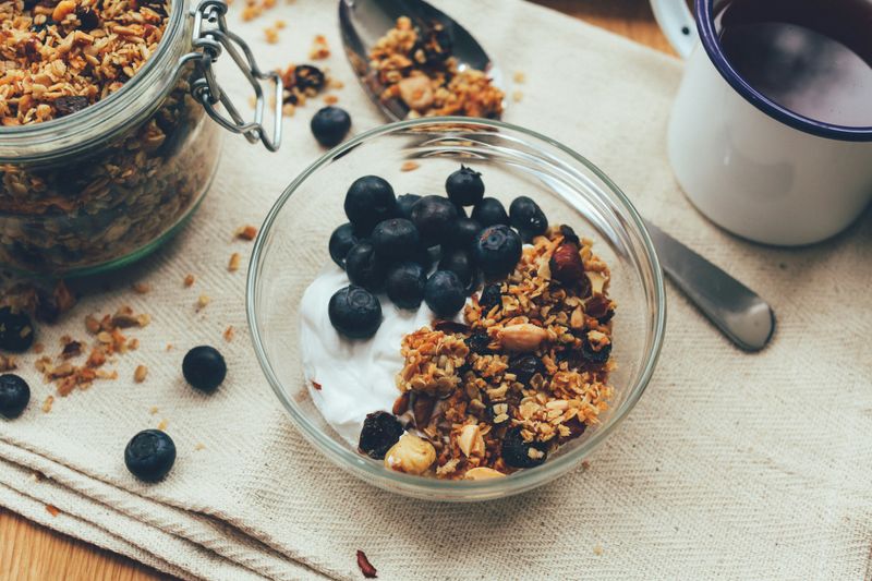 A breakfast showing a bowl with yoghurt, berries and granola