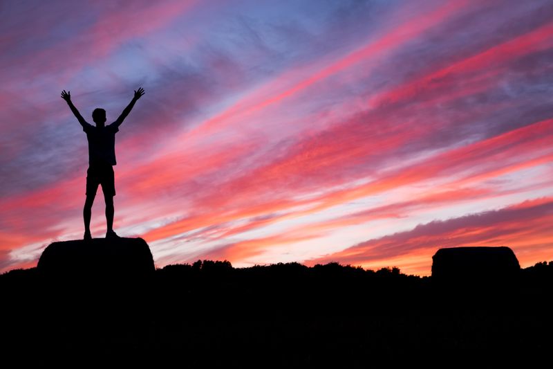 A person standing on top of a mountain at sunset.