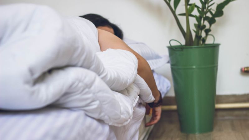 Woman sleeping on a bed covered in a white blanket