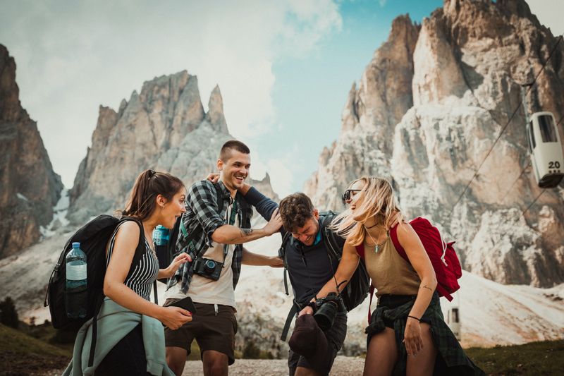 Four traveling backpackers laughing together in the mountains.