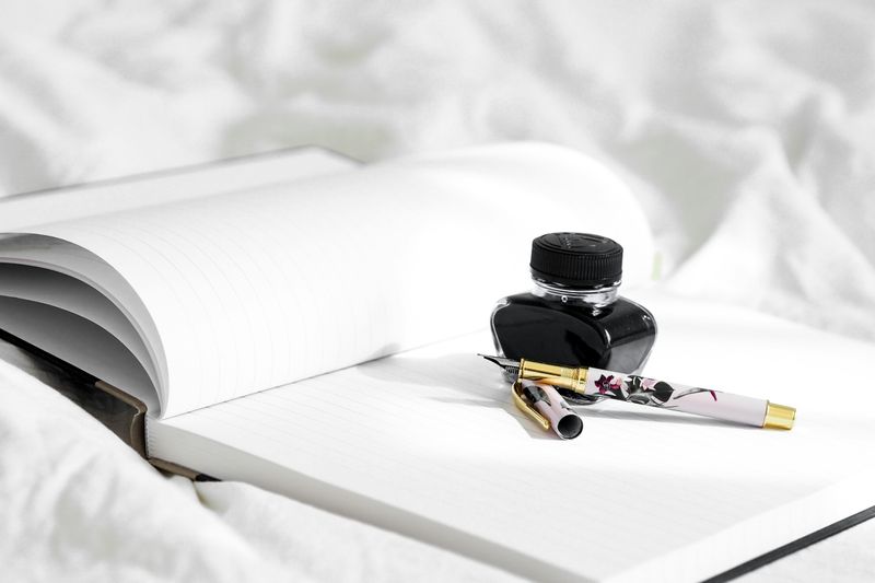 A jar of ink and a pen sitting on an open journal.