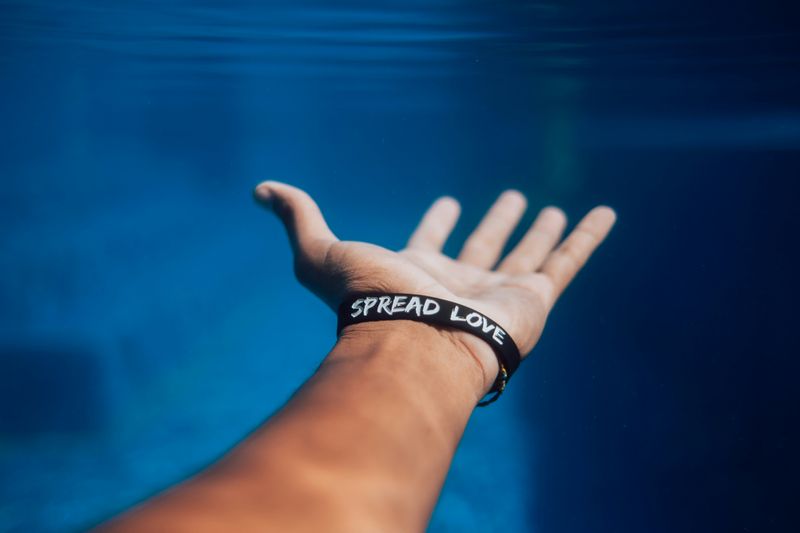 An outstretched hand with a wristband that reads, 'spread love'.