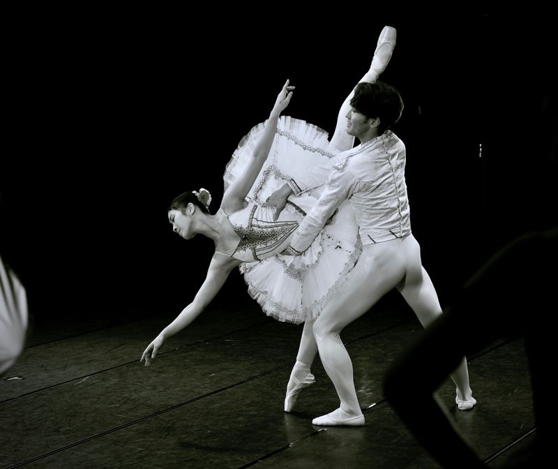 Two ballet dancers performing a move together on stage.