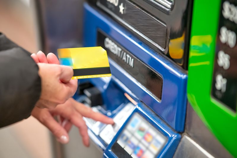 A person putting their debit card into an ATM.