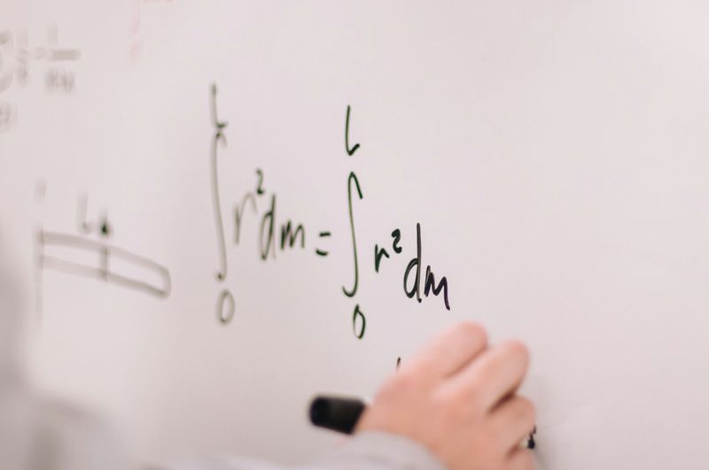 A student writing a complex equation on a whiteboard.