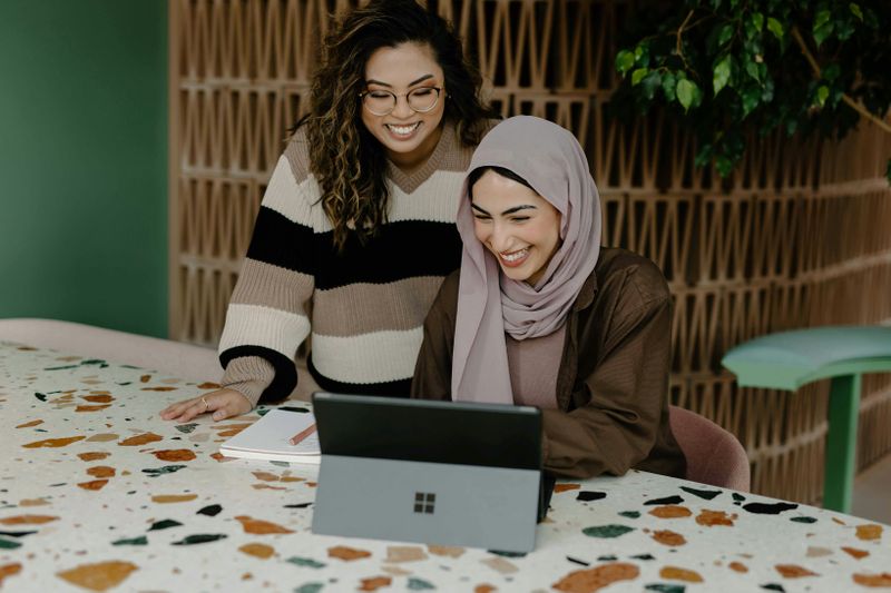 Two women work together at an office desk.