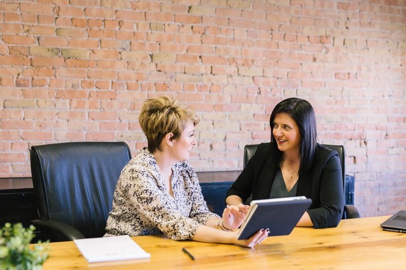 Image of 2 women sittting in office chairs while deep in discussion.