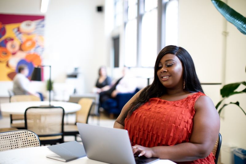 Woman smiling and looking at her laptop screen.