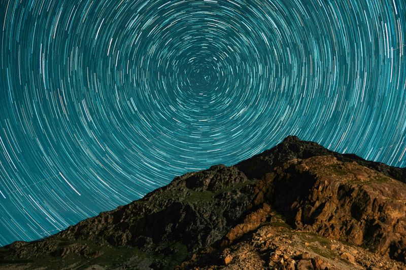 Mountain top with a concentric circle of stars swirling above