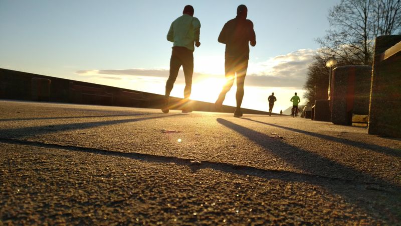 People running along a path at sunset.