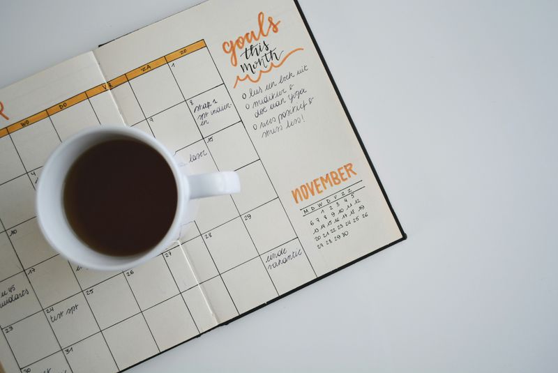 A coffee cup sits on an open calendar that says, 'goals this month'.