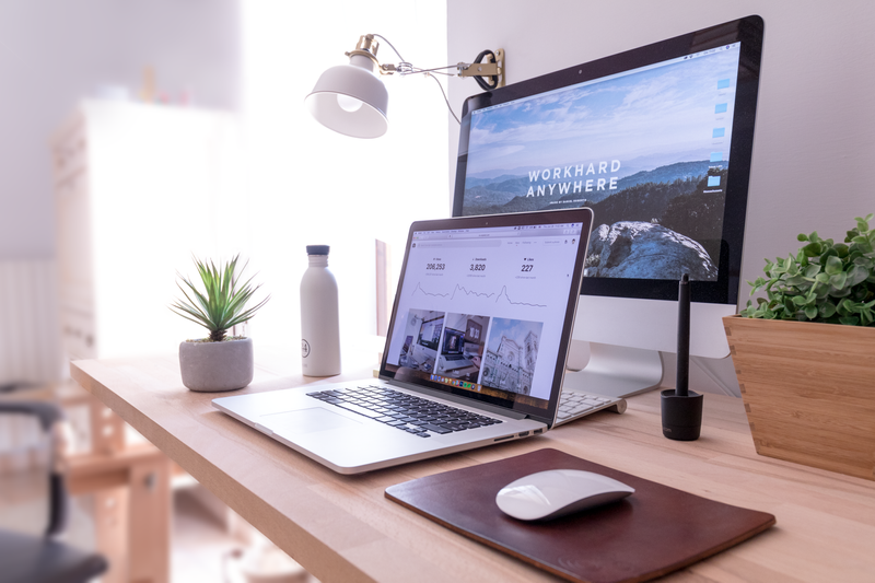 A desk with a laptop on it. A monitor is behind the laptop. The screen on the monitor says, 