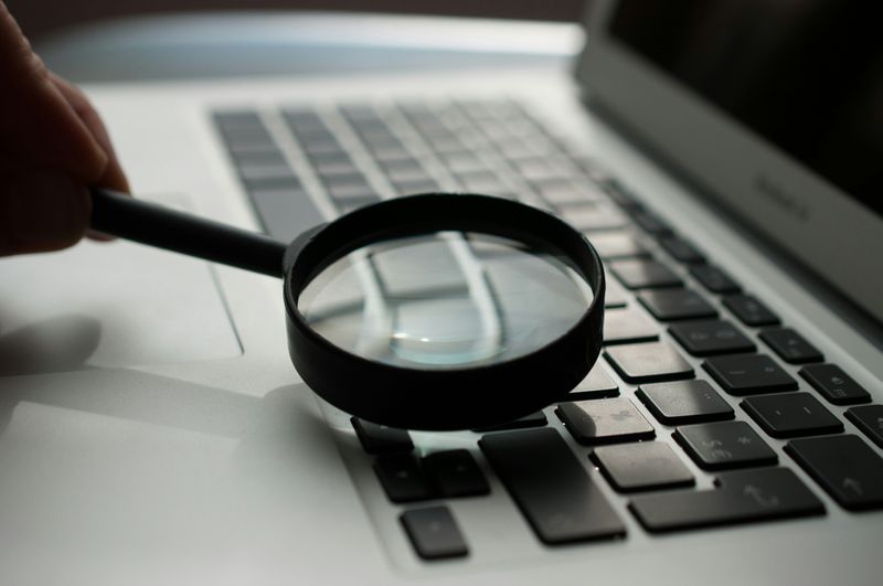 A magnifying glass over a laptop keyboard, taking in information.