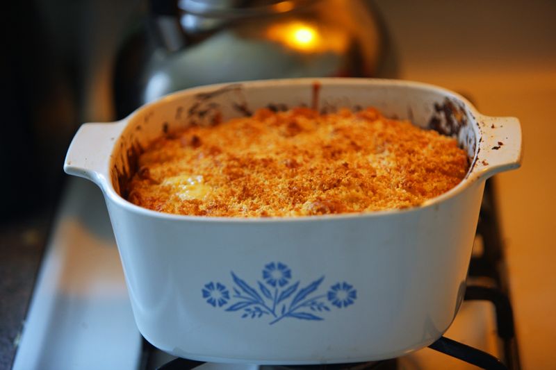 A casserole dish emerging from an oven.