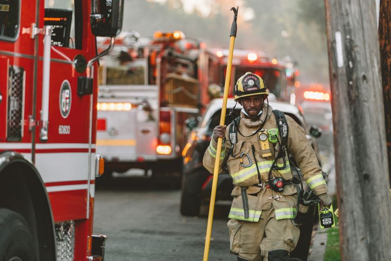 A firefighter standing near firetrucks.