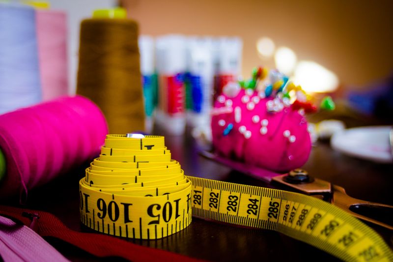 A fashion designer's table with measuring tape, thread rolls, and pins