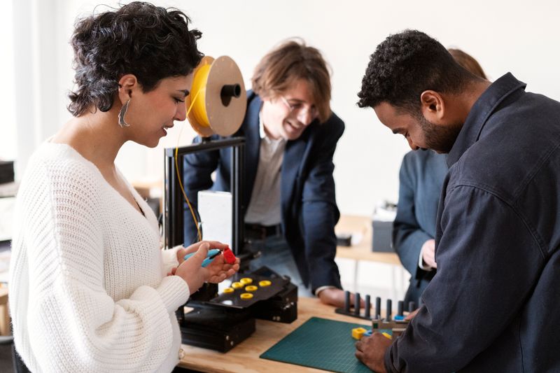 A woman actively working with other professionals on a technical project in a workshop.
