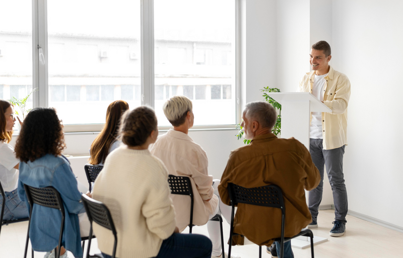 A young man speaking to a group of people.