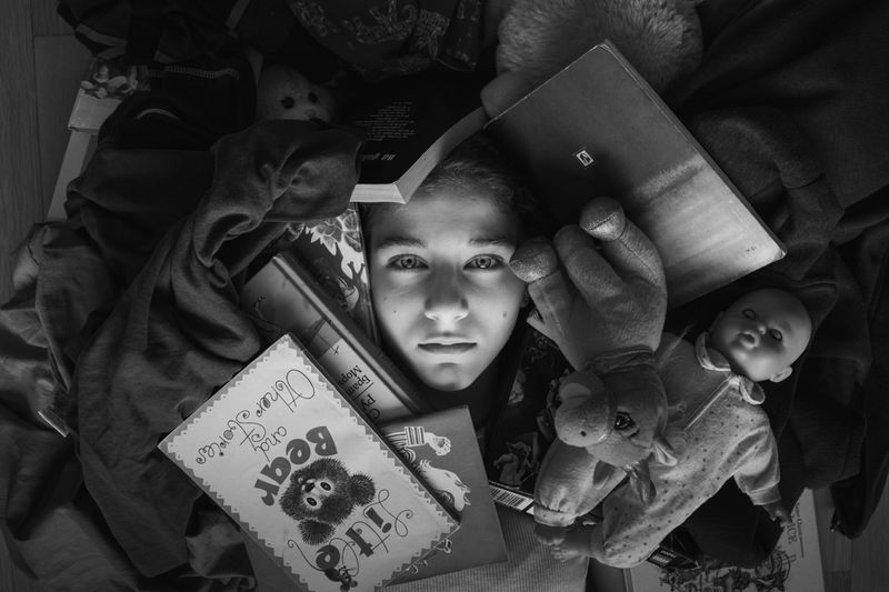 A person lying in their bed buried in in personal items.