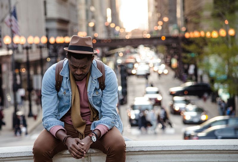 Man sitting outside with his head down looking stressed