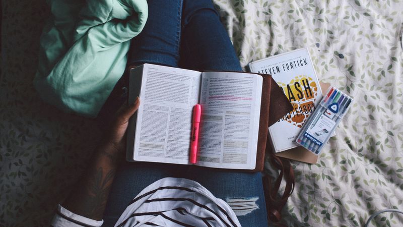 A student holding a book and highlighters.