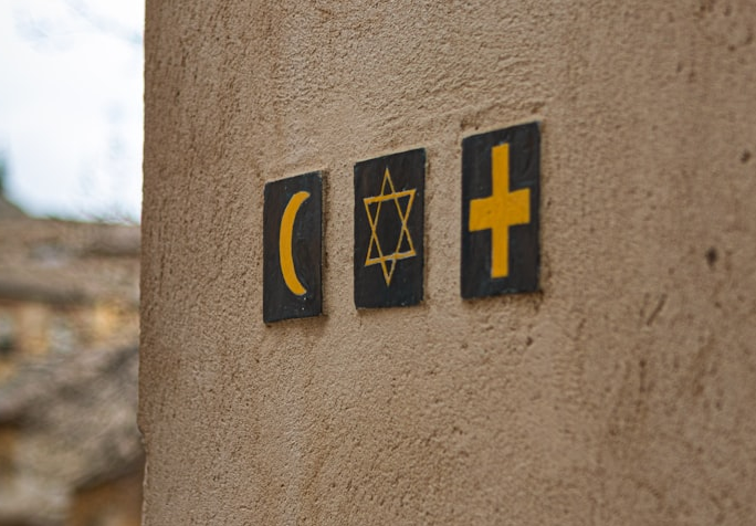 Three religious symbols on a wall that represent Islam (crescent moon), Judaism (star of David), and Christianity (cross).