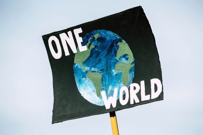 A climate protest sign that reads 'One World' over an image of the Earth.