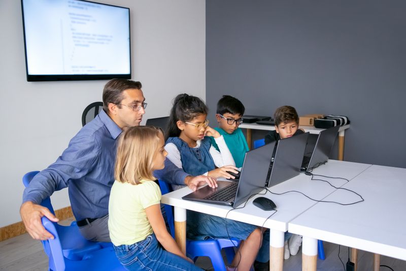 A teacher helping a group of students with an in-class digital activity.