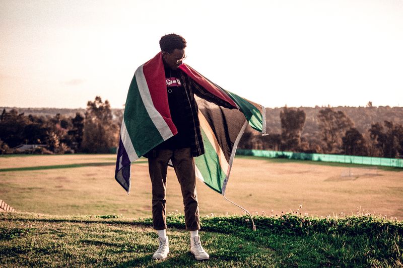 A man wearing the South African flag as a cape.