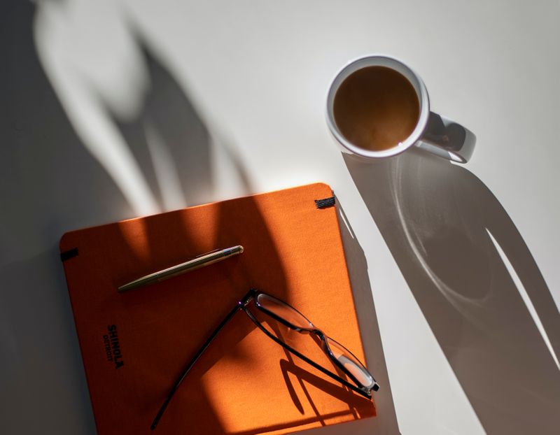 File folder on a desk with a pen, glasses and coffee around it.