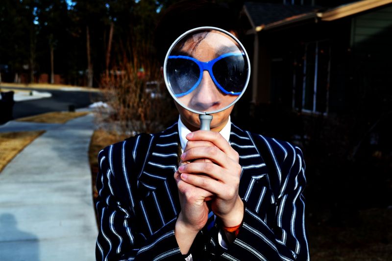 A person in a suit looking through a magnifying glass.