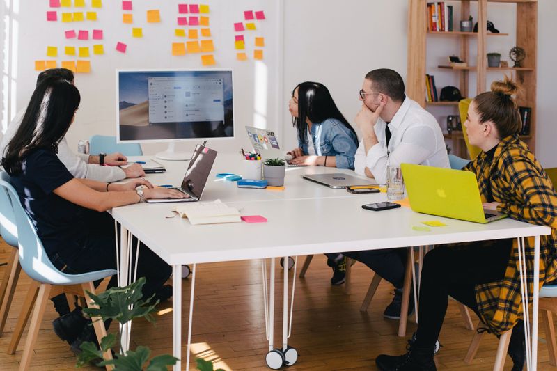 A group of colleagues looking at a computer screen and white board with sticky notes.