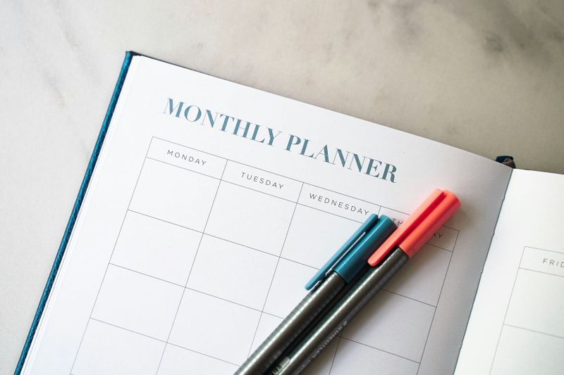 An open monthly planner with two pens resting on top.