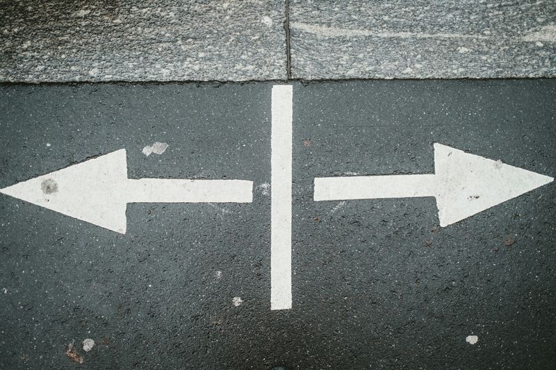Arrows spray painted on a road, pointing in opposite directions.