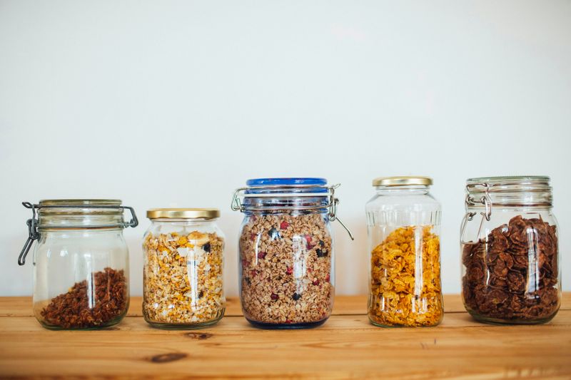 Glass jars on a kitchen counter filled with grains and cereal.