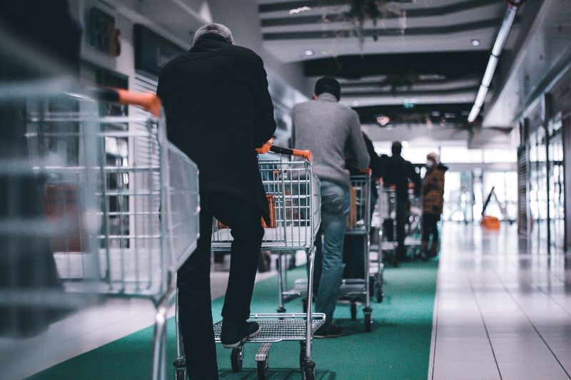 A line of customers with carts at a supermarket. Photo by Adrien Delforge on Unsplash