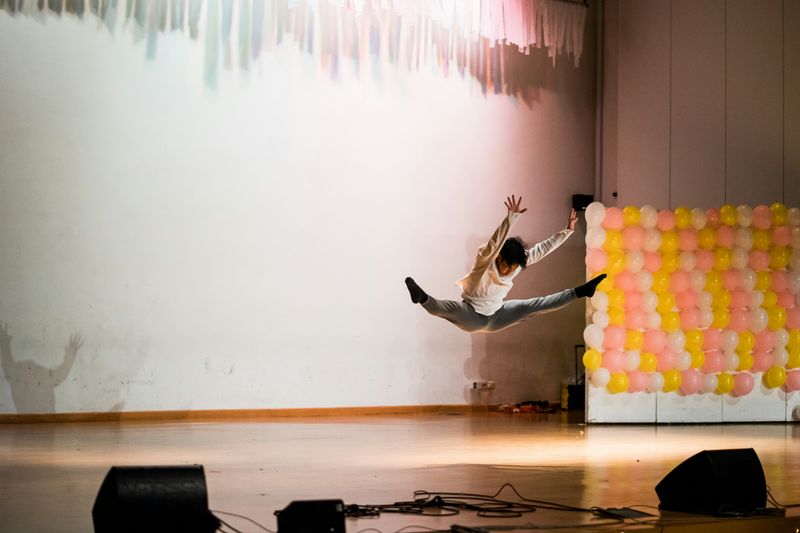 A male dancer on stage, mid-jump.