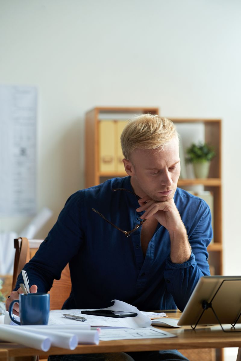 A man sitting at his desking thinking while looking at his computer