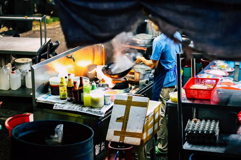 A street food chef preparing food at a kiosk.