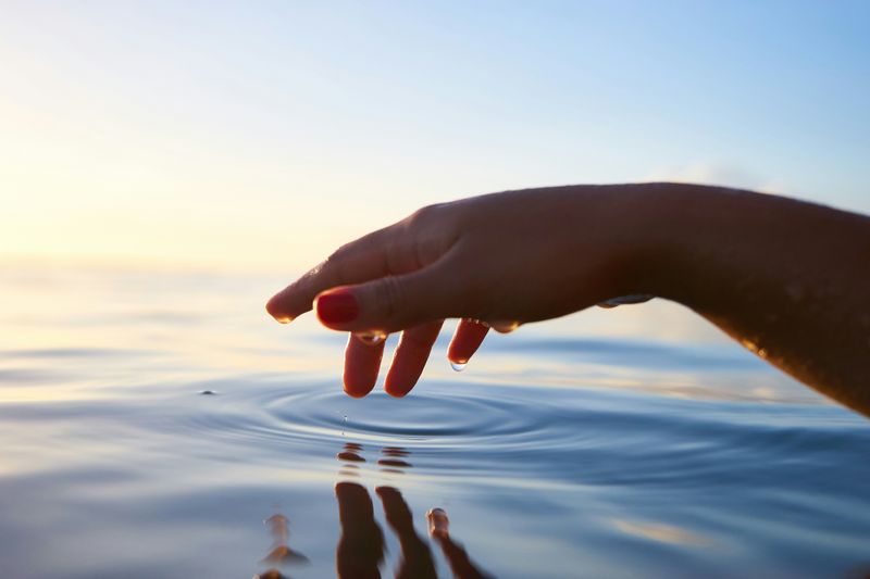 A hand touching a still body of water. 