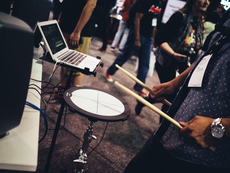 A person playing an electric drum pad on a busy street.